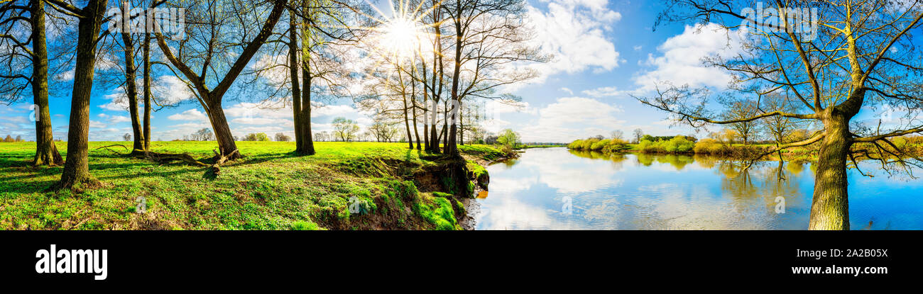 Landschaft im Frühling mit Bäumen und Wiesen am Fluss Stock Photo