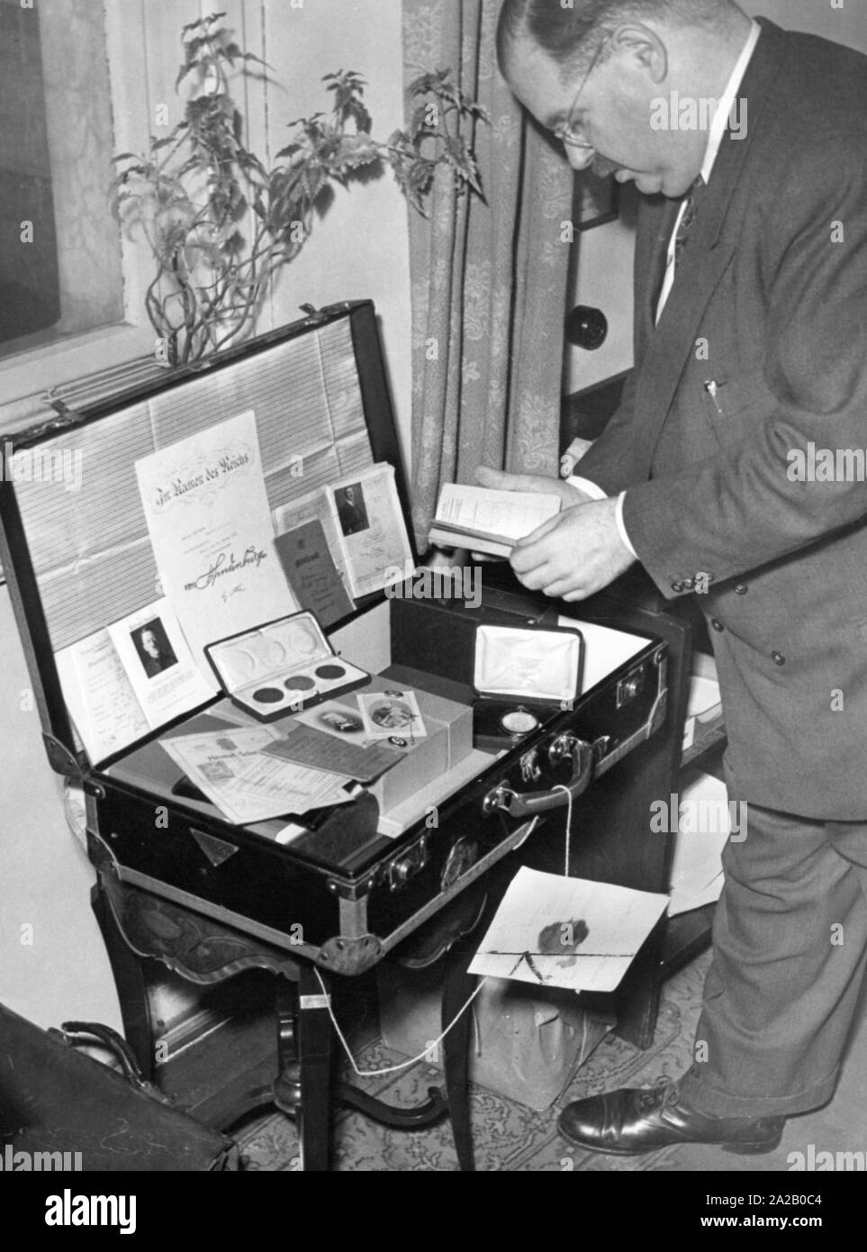 Dr. Philipp Auerbach in front of a suitcase with the belongings of Adolf Hitler. In the opened lid of the suitcase apparently the document of Hitler's appointment as Chancellor. In 1948, a court in Munich adjudicated Hitler's possessions to the Free State of Bavaria. Stock Photo
