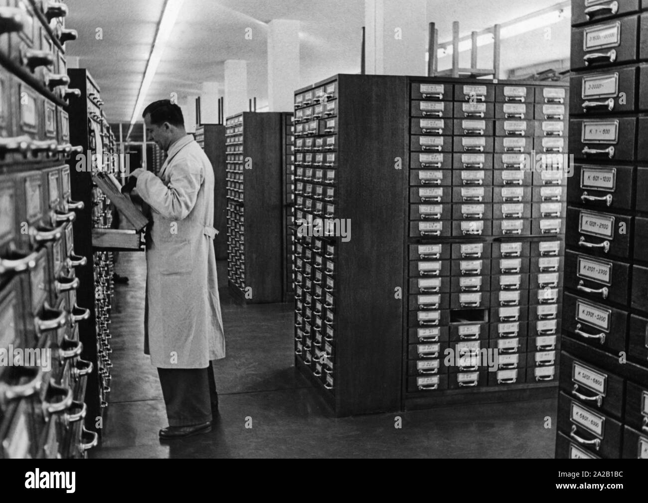 View of files of wanted persons at the Federal Criminal Police Office in Wiesbaden. The files of wanted persons or things, as well as collected relevant information are arranged in numerous filing cabinets. In order to start the police work all files had to be collected from the corridors at this time. The picture shows an employee at one of the filing cabinets. Stock Photo