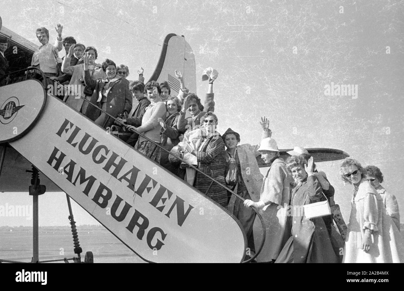 A group of young women from Germany boards the airplane to Melbourne through the gangway at Hamburg Airport.  They all decided to emigrate. At that time the Australian government  attracted immigrants by offering them financial support and many young women and men accepted the offers. Stock Photo