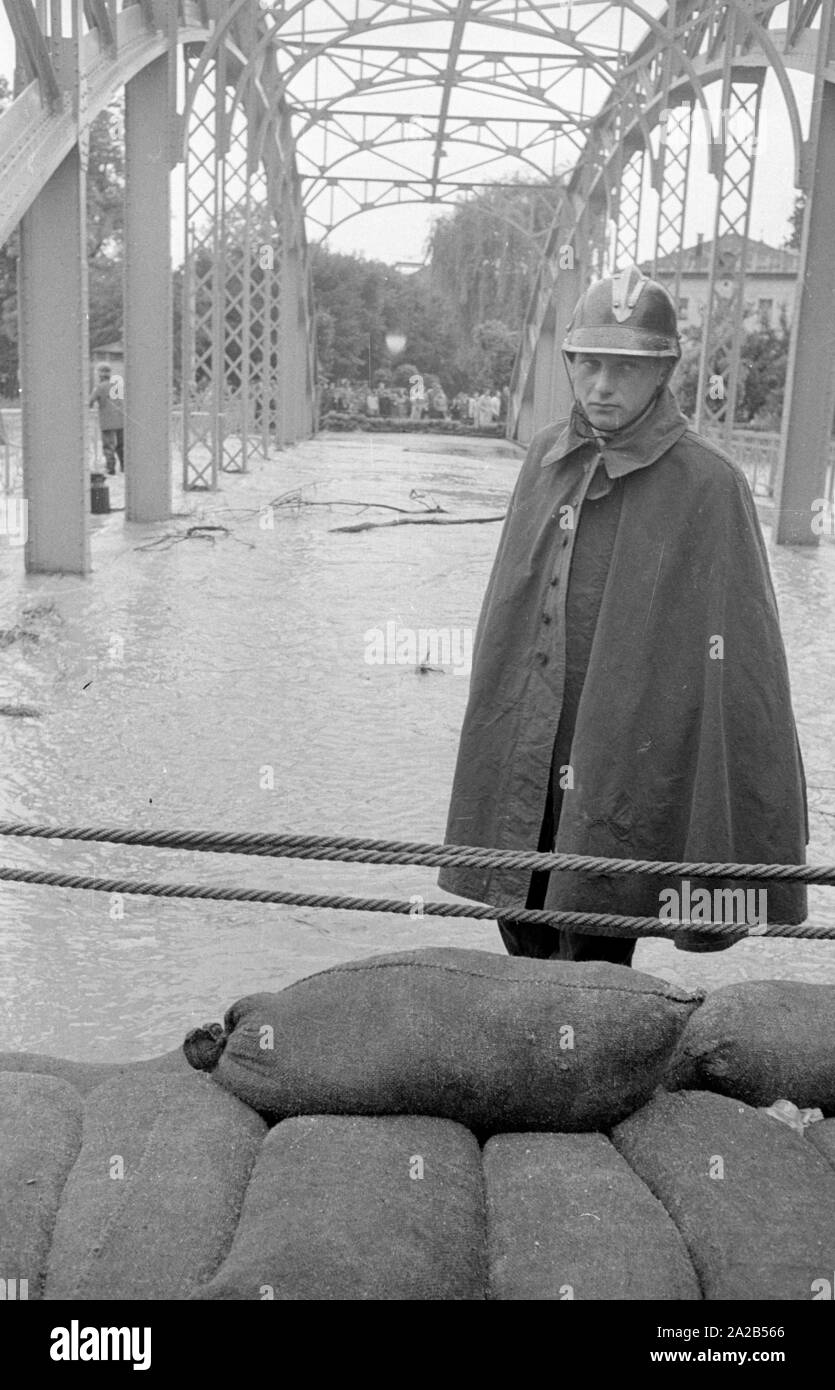 The flood in Passau and other parts of Lower Bavaria (July, 1954) were also referred to as the flood of the century. The Danube, the Inn and the Ilz had overflowed their banks, and flooded towns and villages. Photo of a firefighter standing at a bridge in front of a wall made of sandbags. Stock Photo