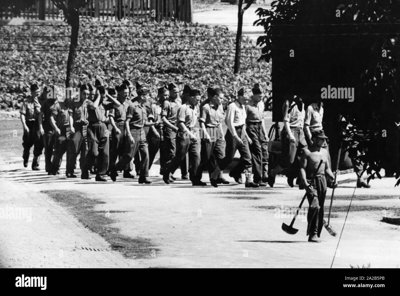 The reorganization camp was the first station of the German Foreign Legionnaires. They march in a row. In the foreground, a legionary cleans the ground (undated photo, probably 1951). Stock Photo