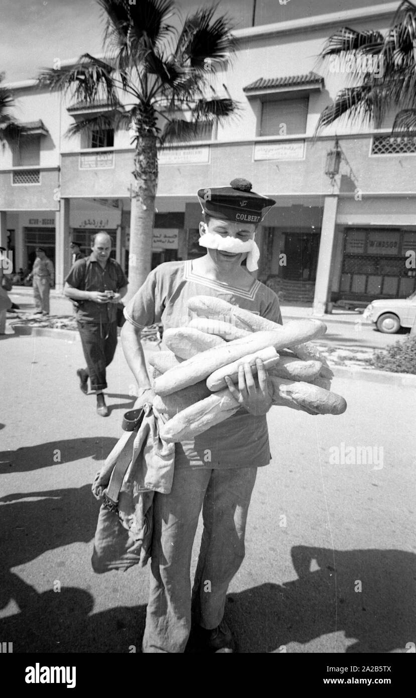 A crew member of the French cruiser Colbert with baguettes. From the report 'Earthquake in Agadir'. The 1960 Agadir earthquake destroyed almost the entire city and is considered the most serious natural disaster in the history of Morocco. Stock Photo