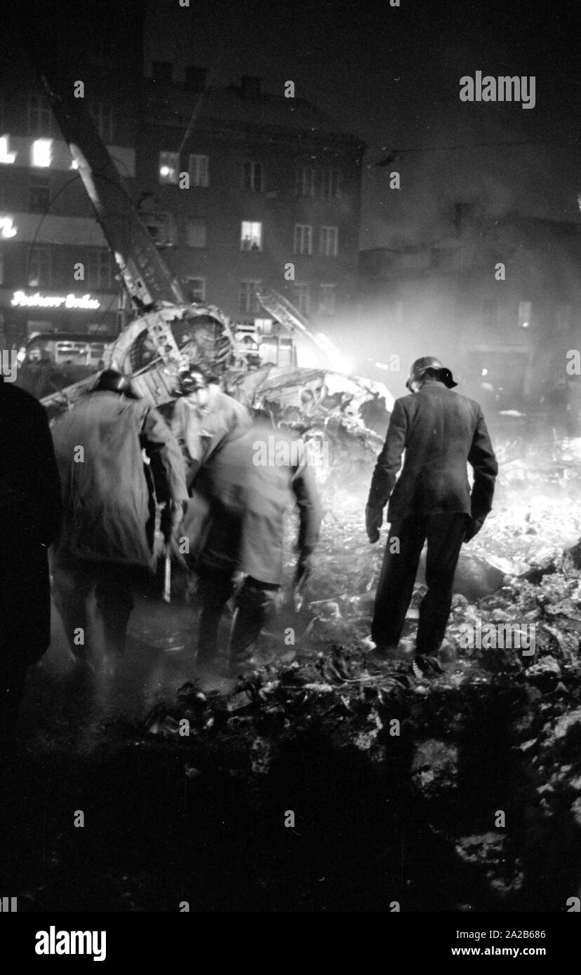 Shortly after the take off from the Munich-Riem Airport a US Air Force transport aircraft of the type Convair C-131-D Samaritan crashed in the area of Bayerstrasse / Martin-Greif Strasse on a tram. 52 people were killed. The picture shows the crash site illuminated with headlights. Relief forces inspect the wreckage and the burned-out skeleton of the aircraft. Stock Photo