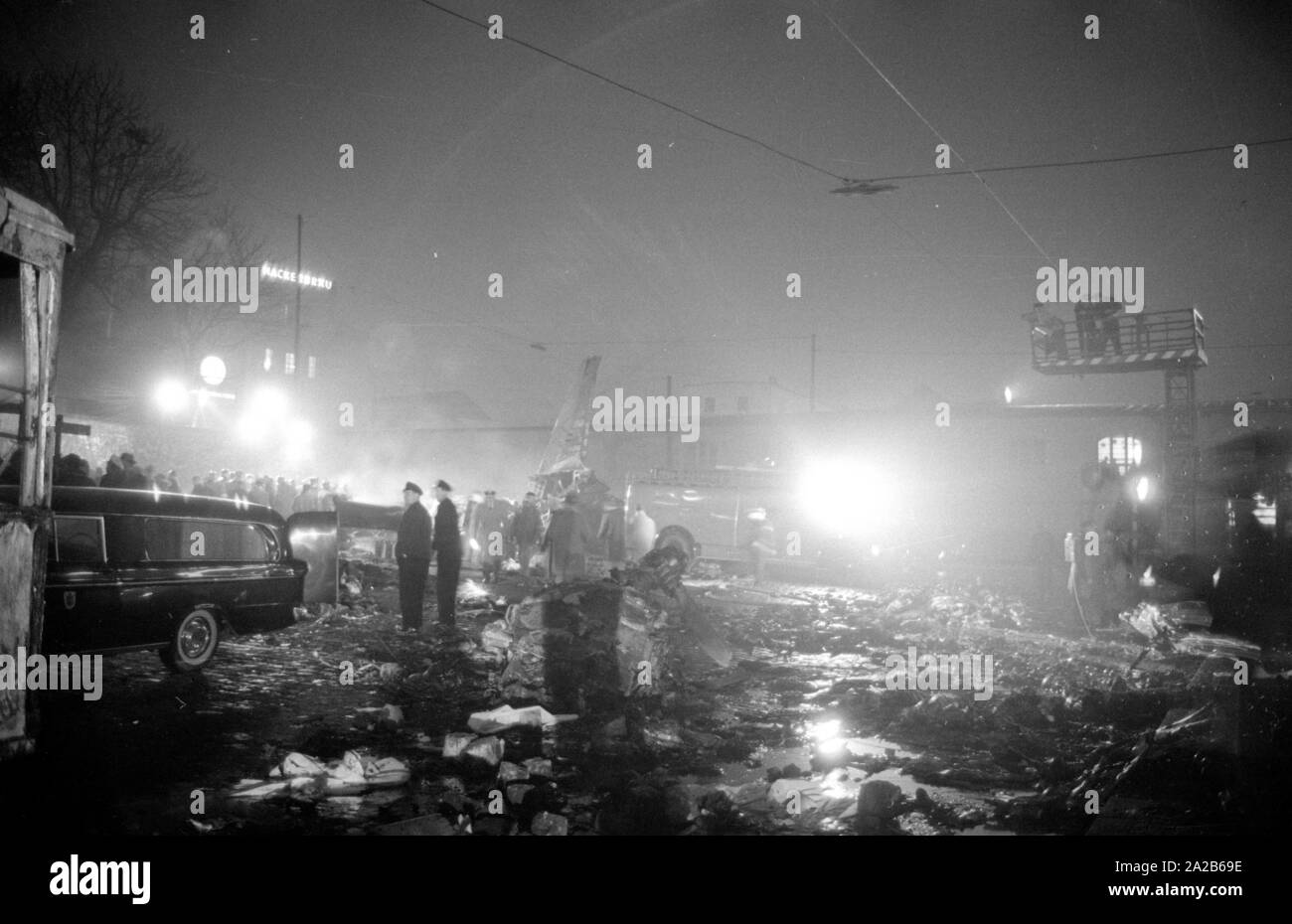 Shortly after the take off from the Munich-Riem Airport a US Air Force transport aircraft of the type Convair C-131-D Samaritan crashed in the area of Bayerstrasse / Martin-Greif Strasse on a tram. 52 people were killed. The picture shows the crash site illuminated with headlights, sightseers, relief forces and wreckage. On the left in the foreground is a hearse. Stock Photo