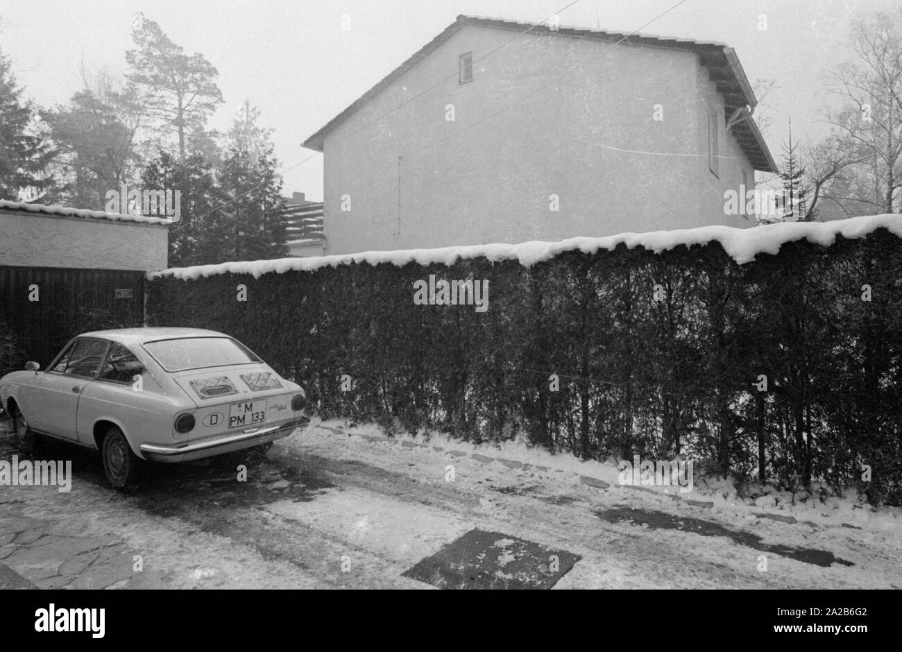A Fiat 850 Coupe is in the driveway of a garage. In the background is a residential house. The car belongs to the photographer Alfred Strobel. Stock Photo