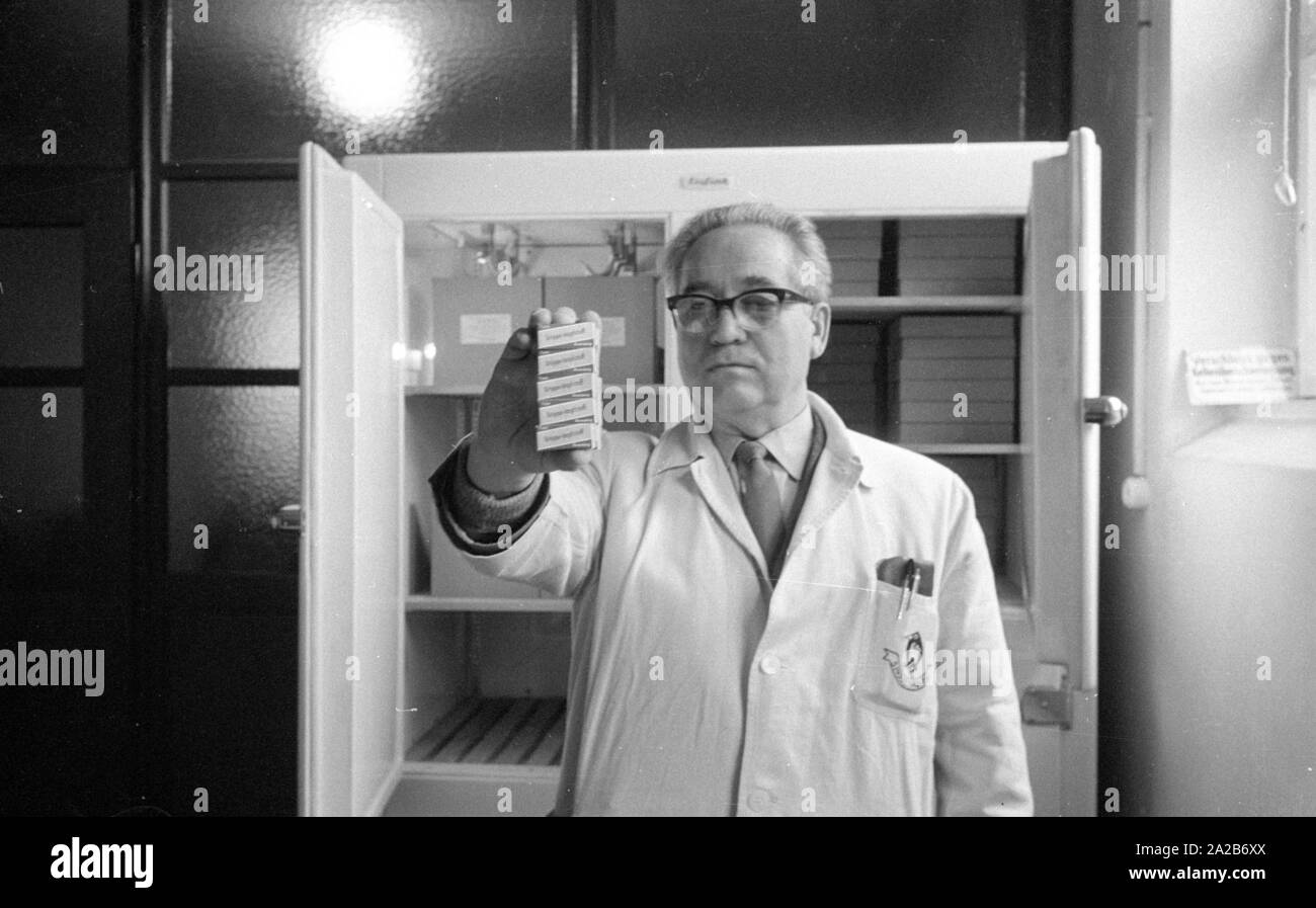 Immunization action in Konstanz with a newly developed flu vaccine of the Ravensberg Chemische Fabrik, An employee of the factory with the new vaccine in front of a medicine cabinet. Around 1960 committees recommended the vaccination against influenza viruses for the first time in the Federal Republic of Germany. Stock Photo