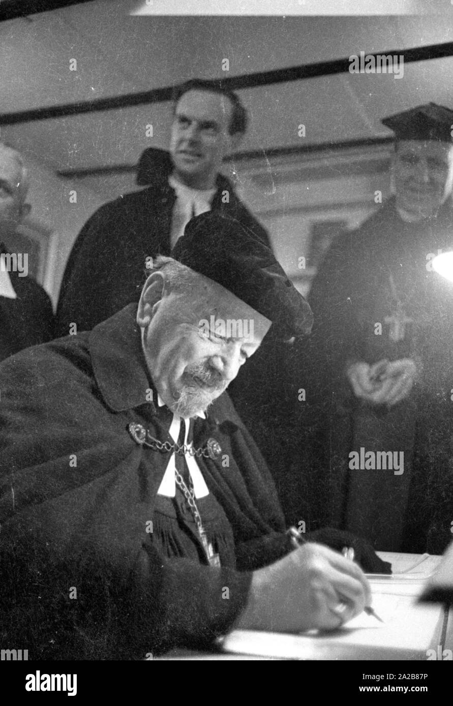 The German bishop, Otto Dibelius, participates at the groundbreaking ceremony  of the 'International Center for Reconciliation' in Coventry. Here, he probably signs the 'book of the new meeting center for reconciliation', which is located in the ruin of the bombed St. Michael's Cathedral. Behind him on the left, Reverend Bill Williams, the pastor of St. Michael's Cathedral. Stock Photo