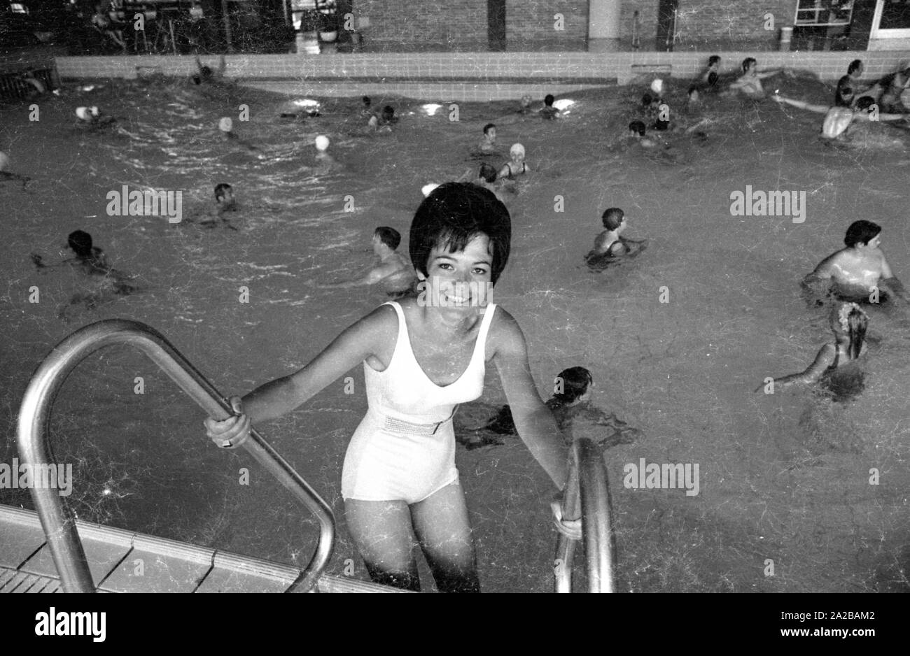 A woman in a white swimsuit poses for a photo while she is getting into a swimming  pool Stock Photo - Alamy