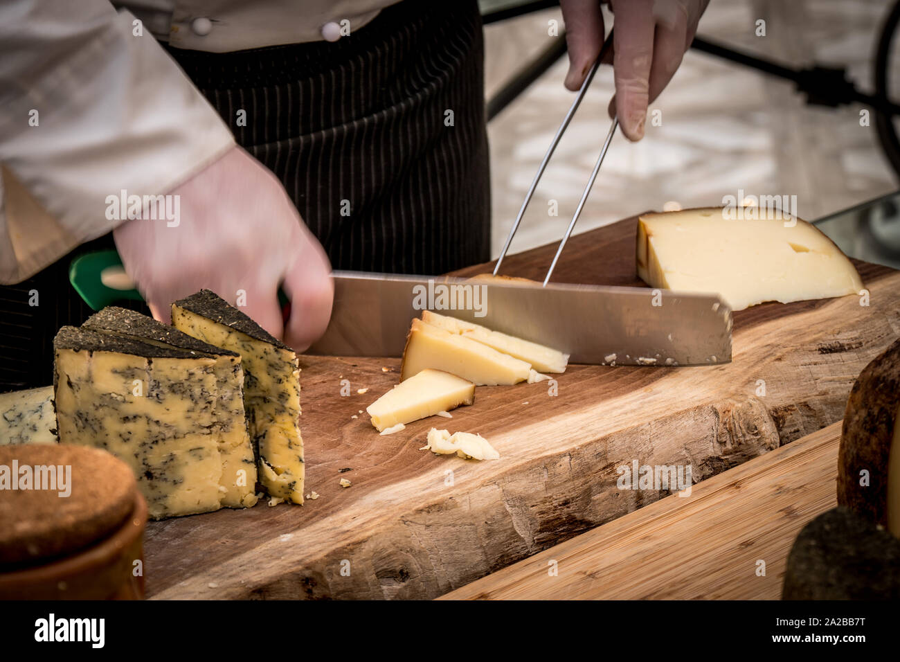 Chef In Restaurant Cutting cheese on wood table, Wedding Buffet Stock Photo