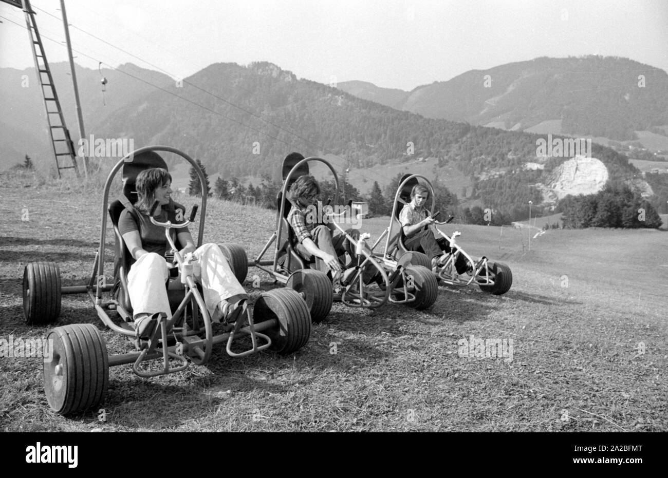 Young people ride "downhill carts", here called "sloper". Here, the driver  and the cart are carried to the mountain by a ski lift, and then they  descend again, taking advantage of gravity