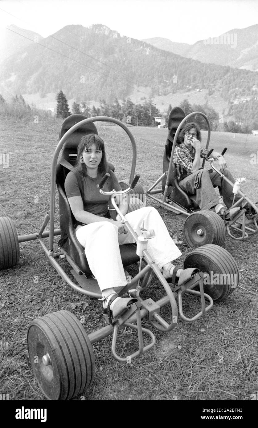 Young people ride "downhill carts", here called "sloper". Here, the driver  and the cart are carried to the mountain by a ski lift, and then they  descend again, taking advantage of gravity