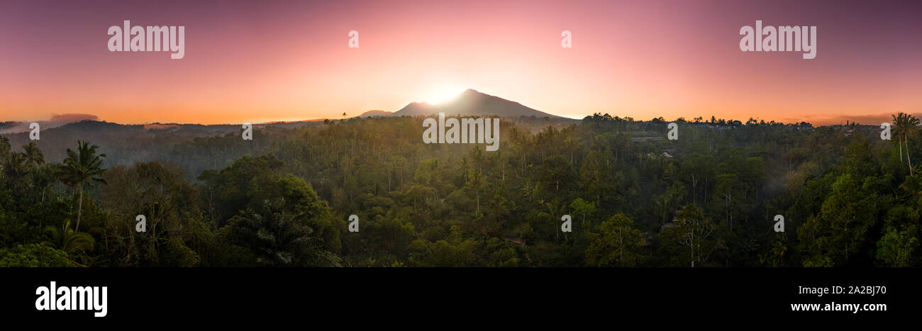Majestic volcano at sunrise surrounded by dense rainforest Stock Photo