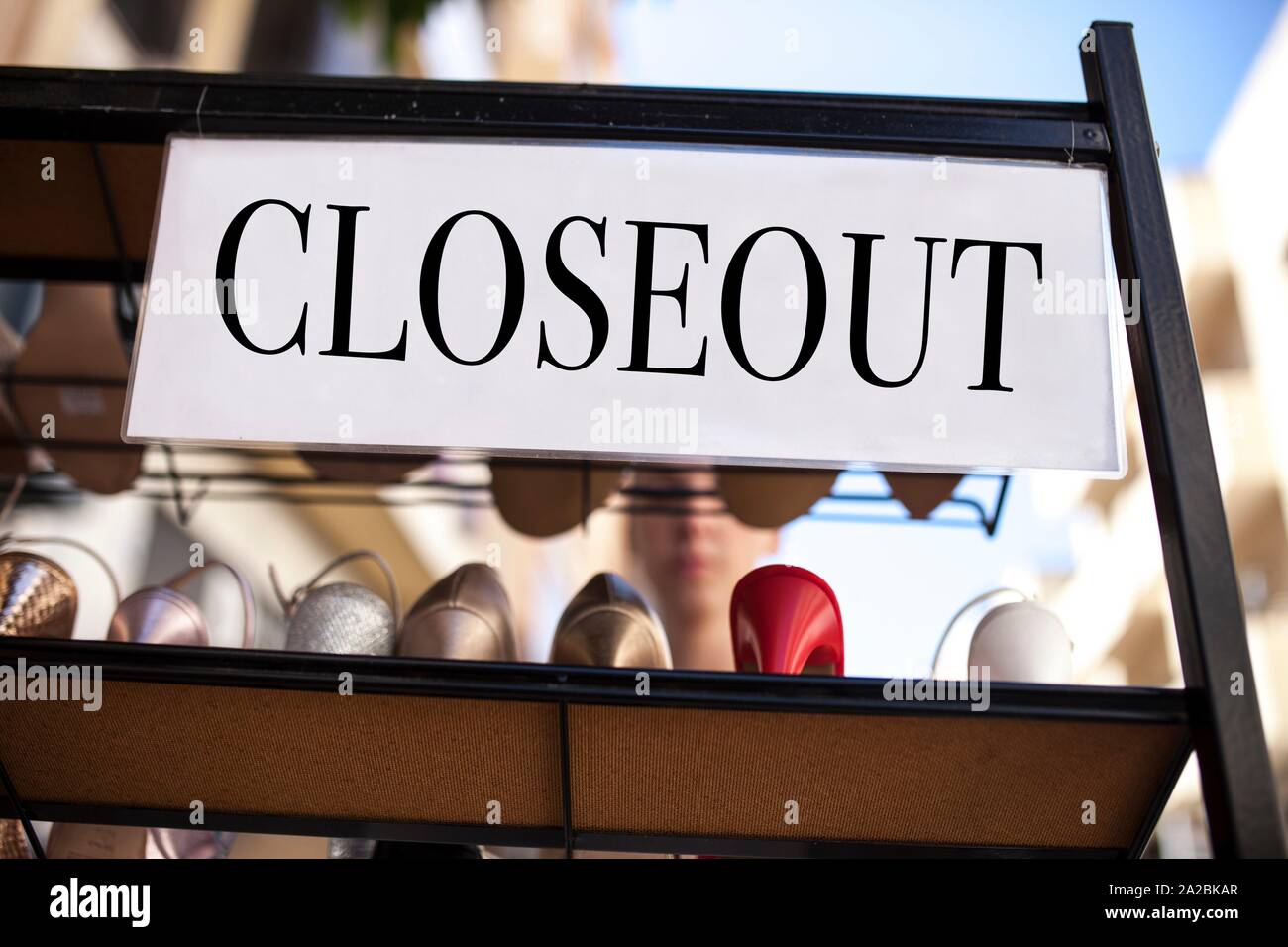 Lady shoes on closeout sales. A woman looks at the sales stand places outdoors the shop. Stock Photo