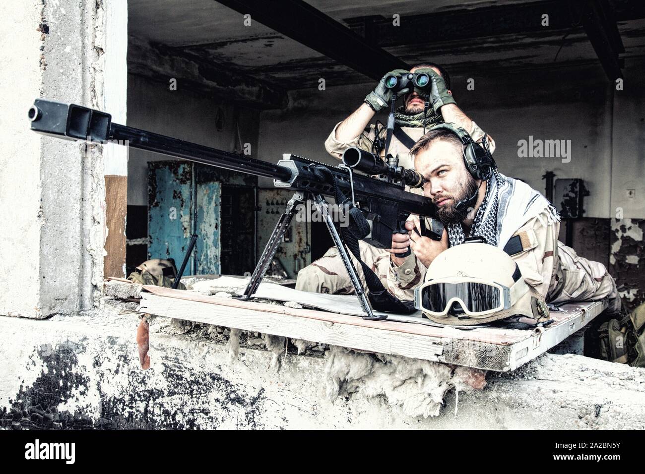 A U.S. paratrooper scans for targets behind a Barrett .50-caliber sniper  rifle while on a