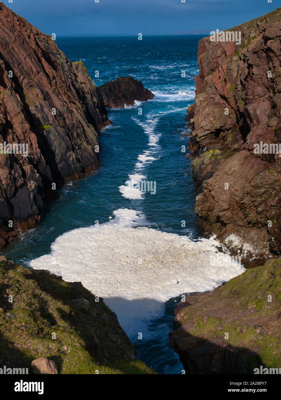 Sea spume or sea foam formed in West Ness Geo near North Ham on the island of Muckle Roe in Shetland, UK. Stock Photo