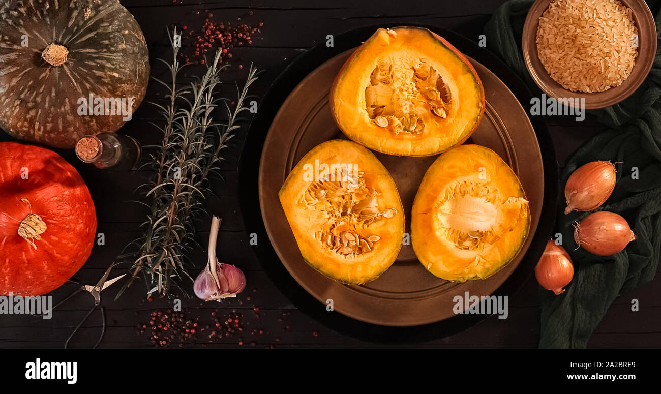 Ingredients for the risotto with red kury squash photographed on a black wood table from the top. Stock Photo