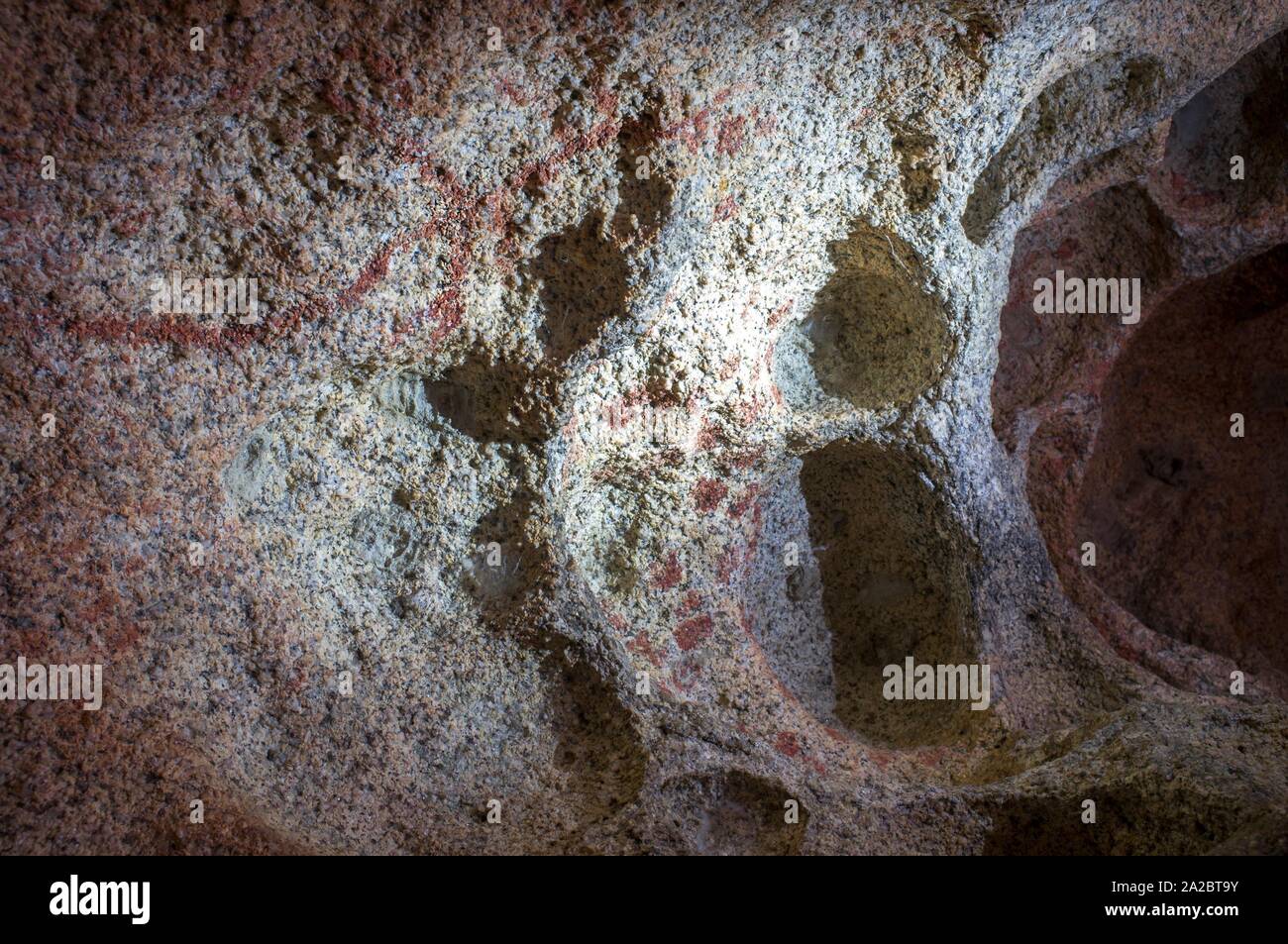 Prehistoric schematic paintings inside granite boulder at Natural Monument of Los Barruecos, Extremadura, Spain. Branch-shaped and dotted paintings. Stock Photo