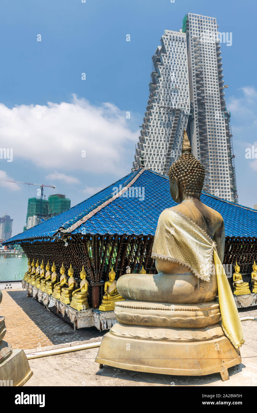 A Buddhist statue at the Seema Malaka Temple on Lake Beira sits against a background of urban development in the Sri Lankan capital of Columbo. Stock Photo
