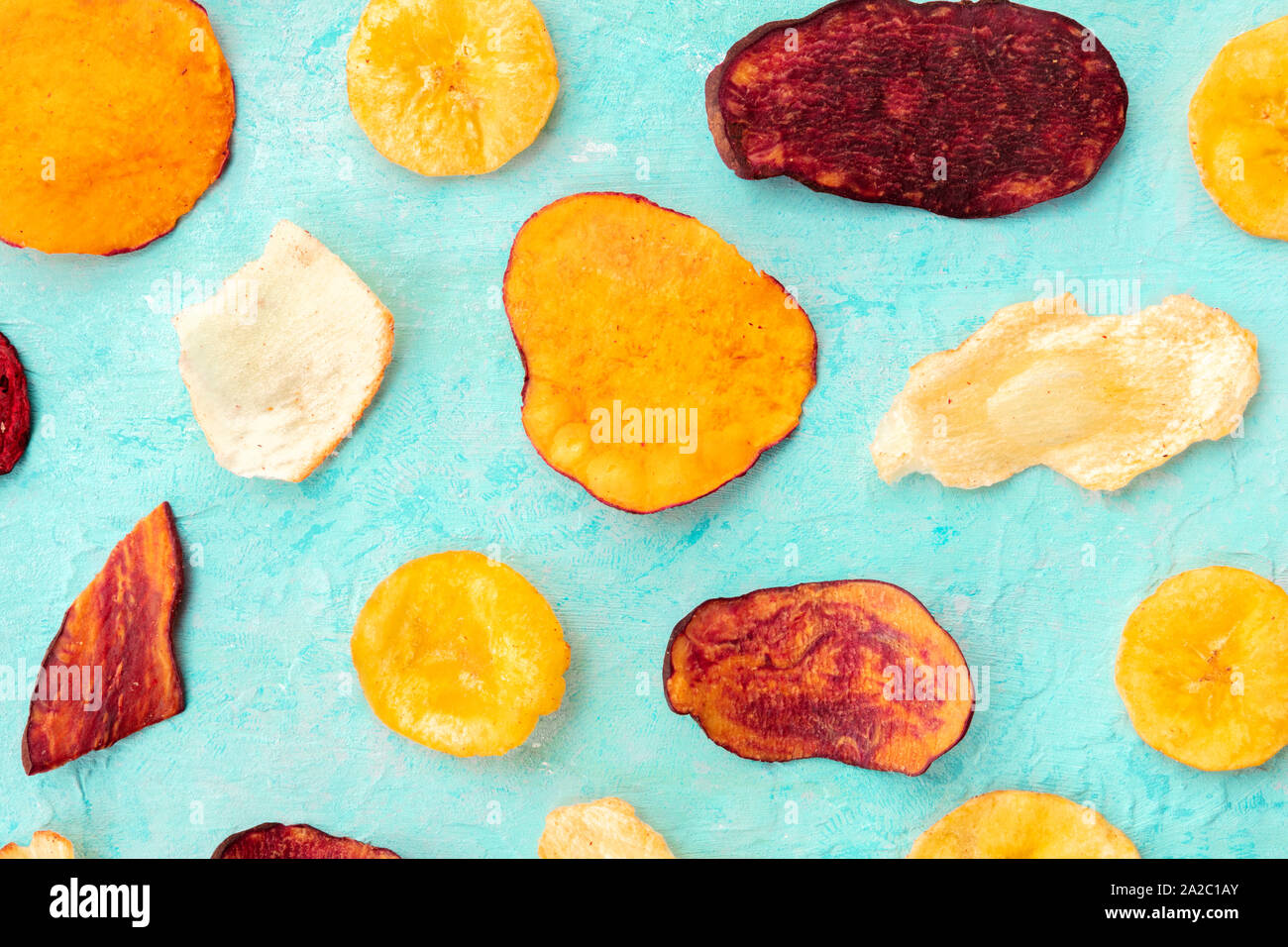 Dry fruit and vegetable chips, top shot. Healthy vegan snack, an organic food flat lay pattern on a teal blue background Stock Photo