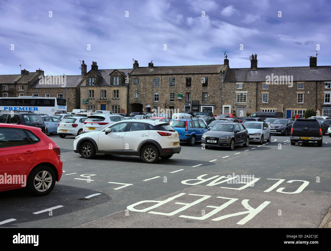 The Market place and car park in the centre of rural Masham with shops and traditional buildings