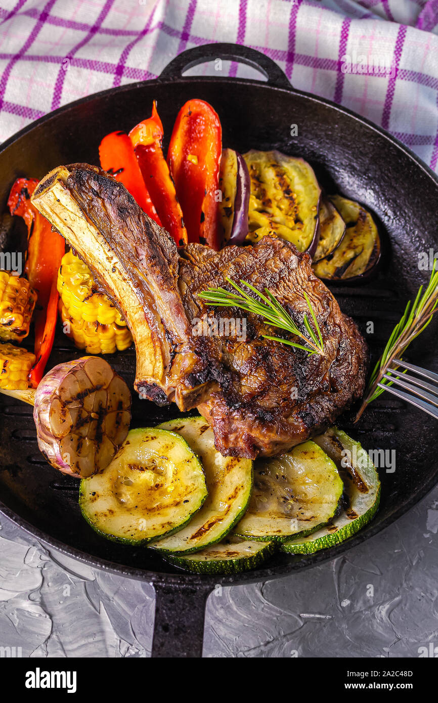 Juicy steak with grilled vegetables served in a cast iron pan. Life style. Top view Stock Photo