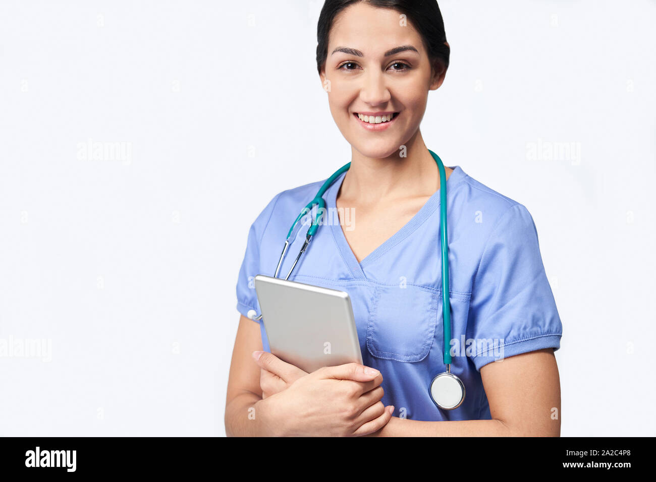 Studio Portrait Shot Of Female Nurse Wearing Scrubs Using Digital Tablet Stock Photo