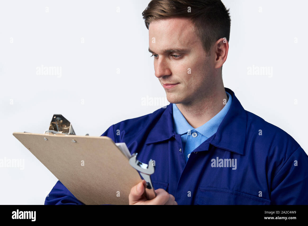 Male Engineer With Clipboard And Spanner Against White Background Stock Photo