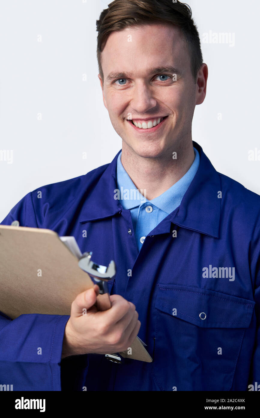 Studio Portrait Of Male Engineer With Clipboard And Spanner Against White Background Stock Photo