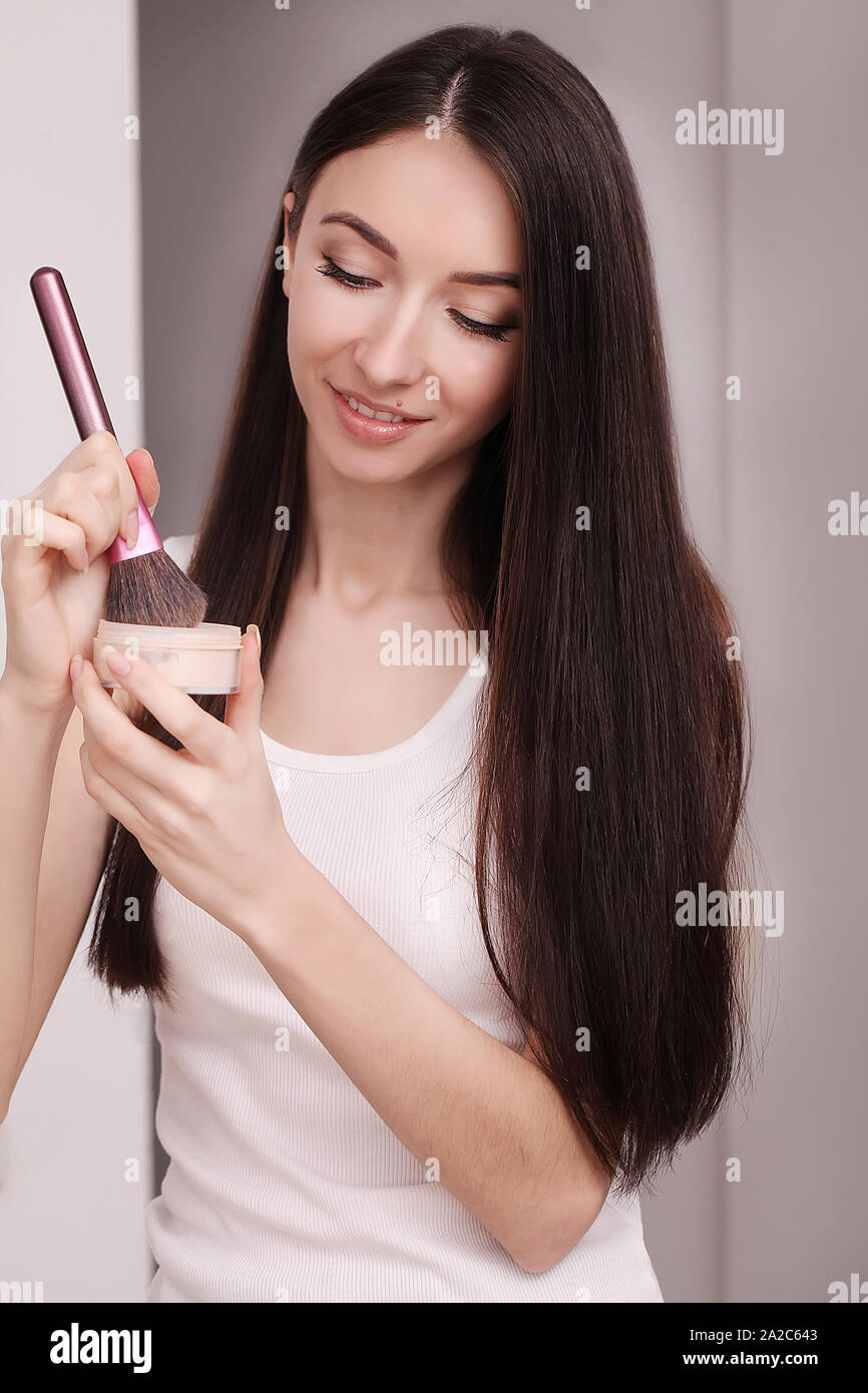 A young woman applied liquid foundation on her face with a brush Stock Photo
