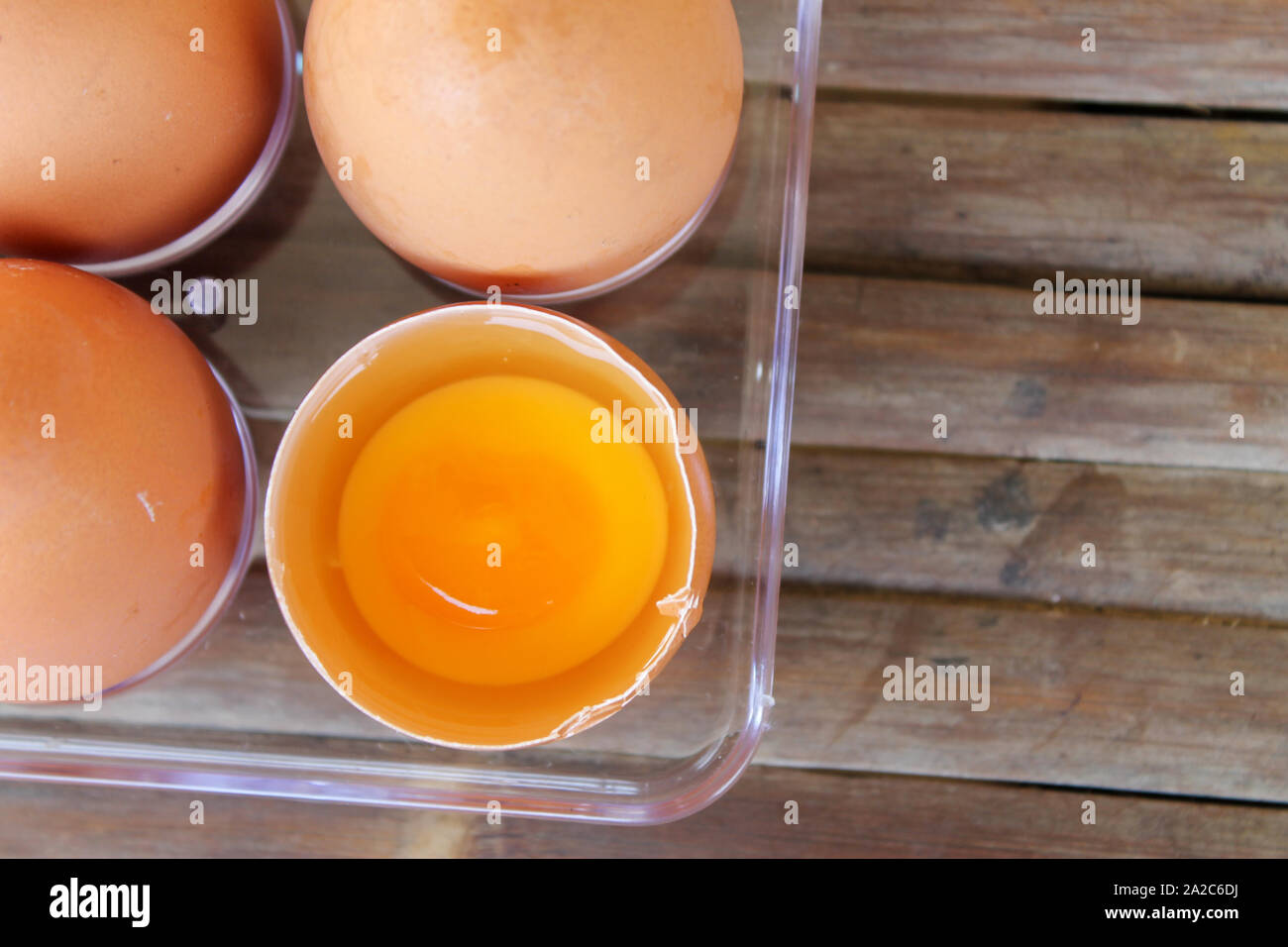 top view of broken eggshell with yellow yolk near eggs in plastic box Stock Photo