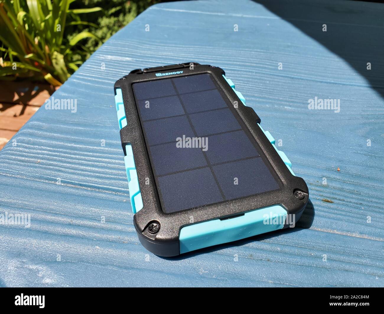 Renogy EPower solar-powered emergency cellular phone charger, designed for use during camping or power outages, charging in sunlight on a blue surface outdoors, San Ramon, California, August 2, 2019. () Stock Photo