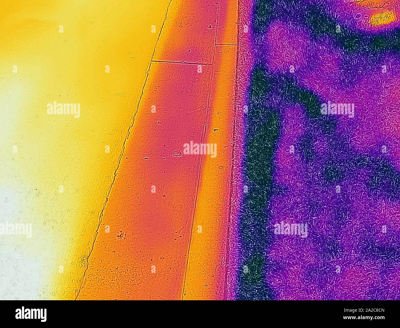 Thermal camera thermographic image, with light areas corresponding to higher temperatures, contrasting (L to R), very hot black asphalt road surface, colder white concrete gutter, and cool grassy area, illustrating the urban heat island effect, in which a greater number of paved surfaces results in higher temperatures in cities, San Ramon, California, September 2, 2019. () Stock Photo