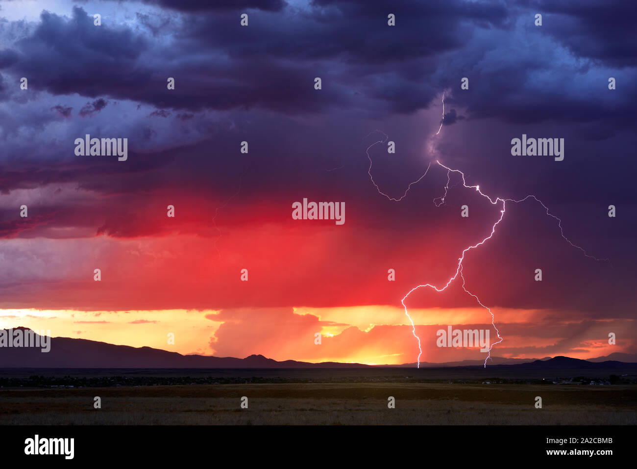Lightning strikes through a colorful sunset sky as a thunderstorm moves