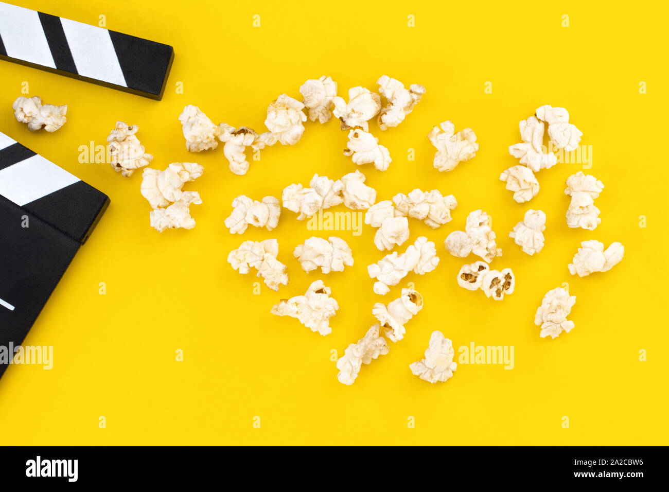 Popcorn and clapperboard on colorful background. Top view. Stock Photo
