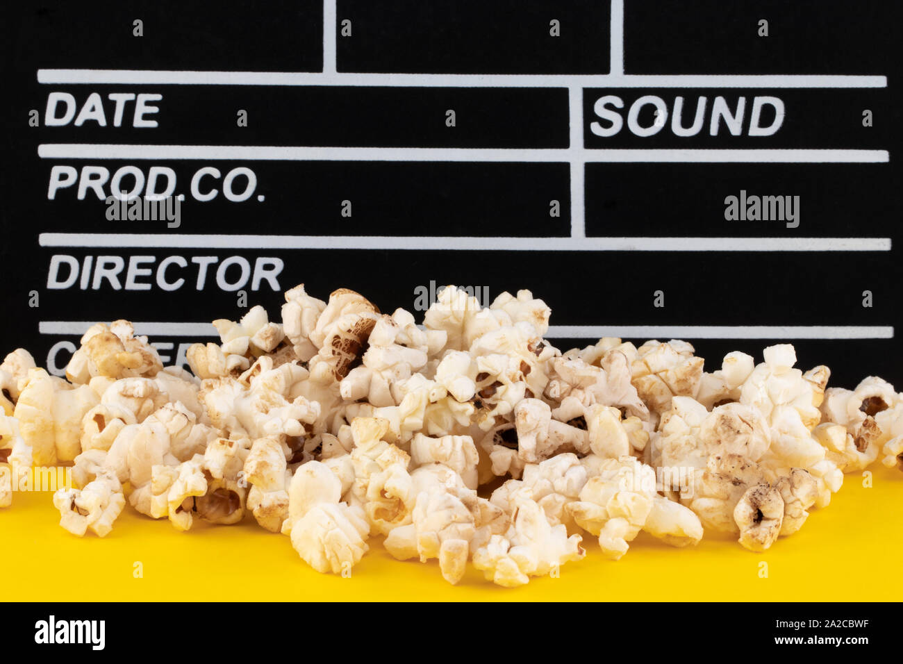Popcorn and clapperboard on colorful background. Stock Photo