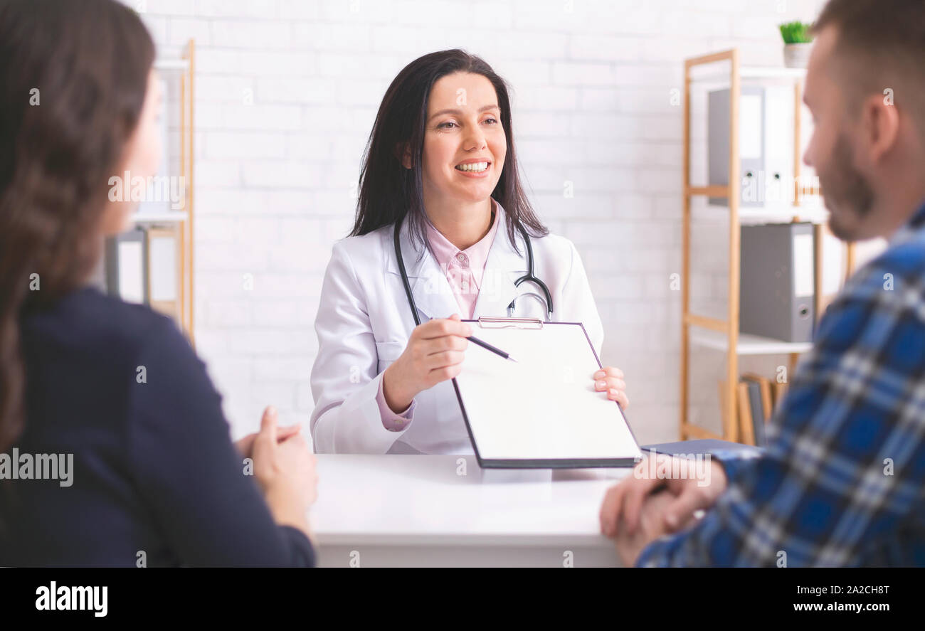 Friendly family doctor explaining prescription to patients at clinic ...