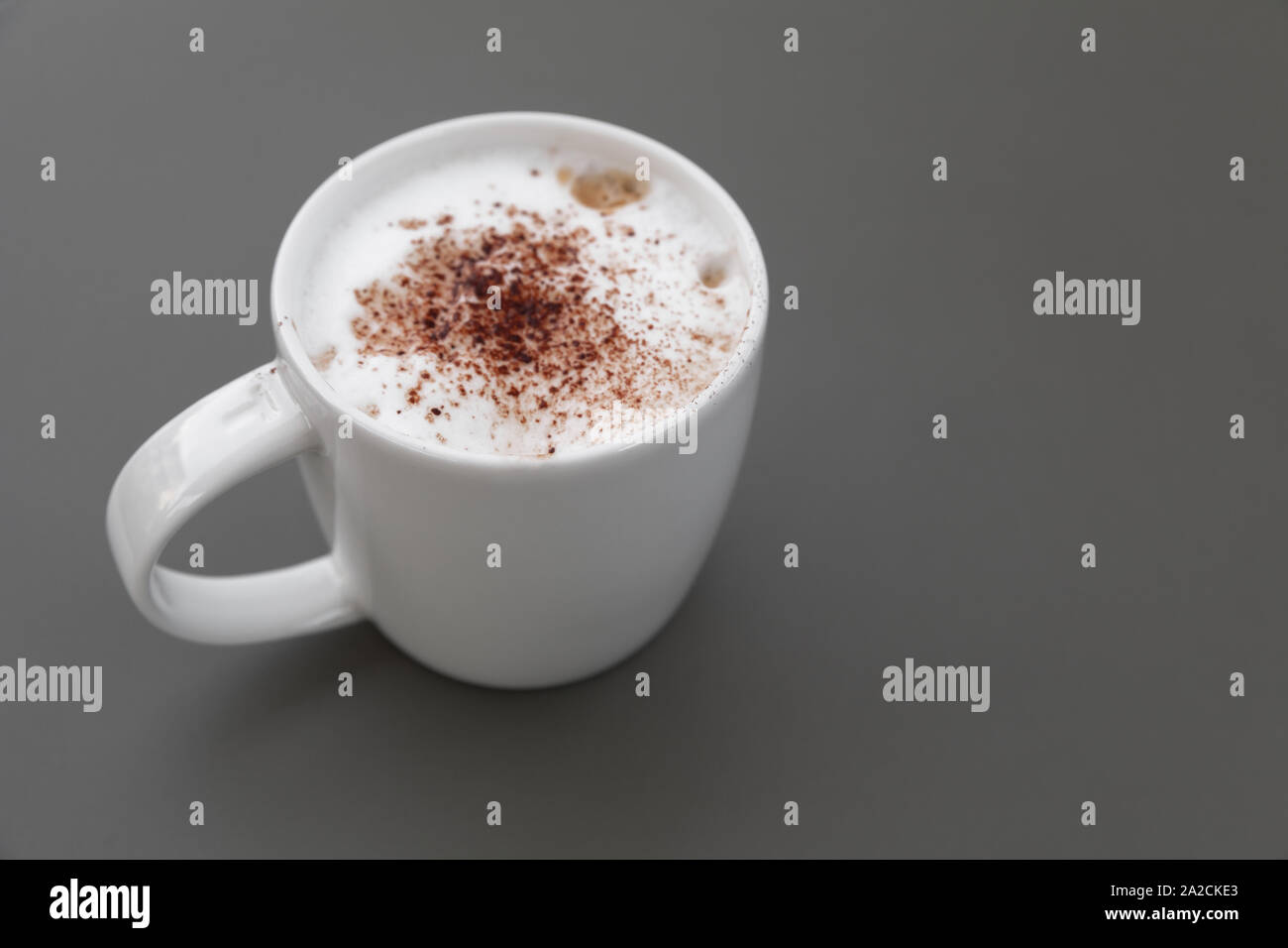 One Cappuccino. Cup of coffee with milk foam and cinnamon stands on a gray table. Close-up photo with soft selective focus Stock Photo