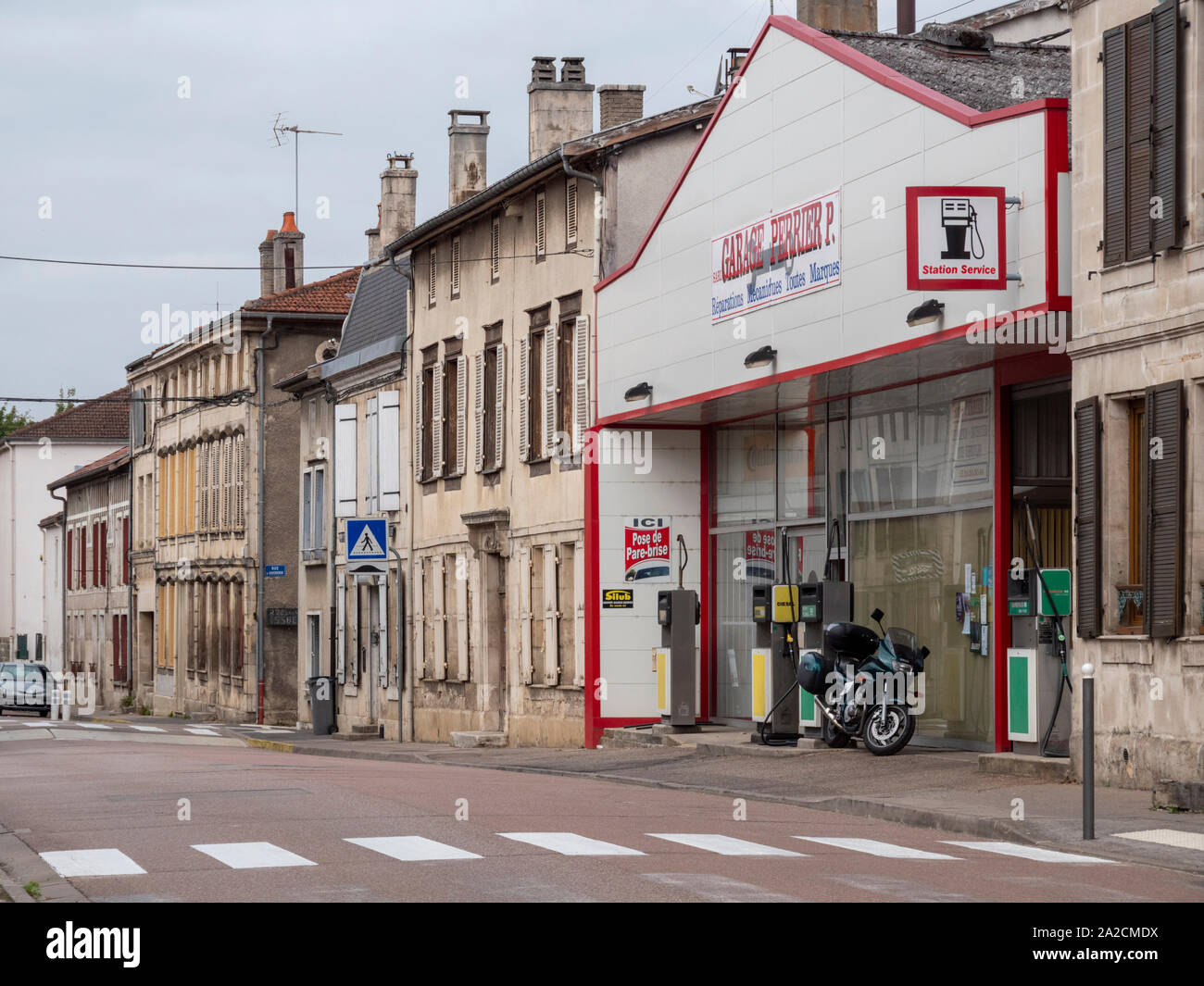 A street scene in the French village of Wassy in the Champagnes-Ardennes region of France showing a garage and shops and buildings lining the road. Stock Photo