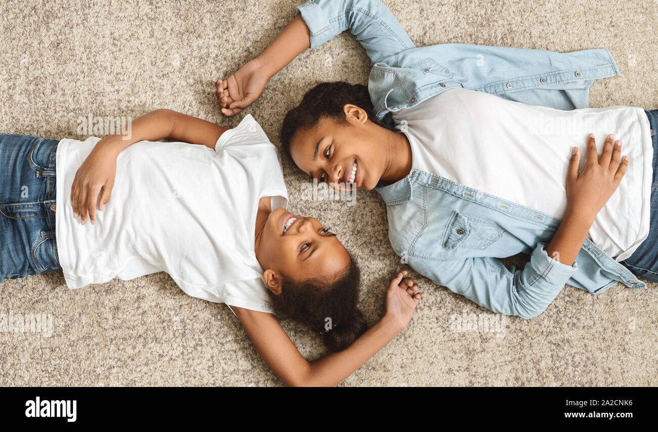 Two lovely sisters laying on floor face to face Stock Photo