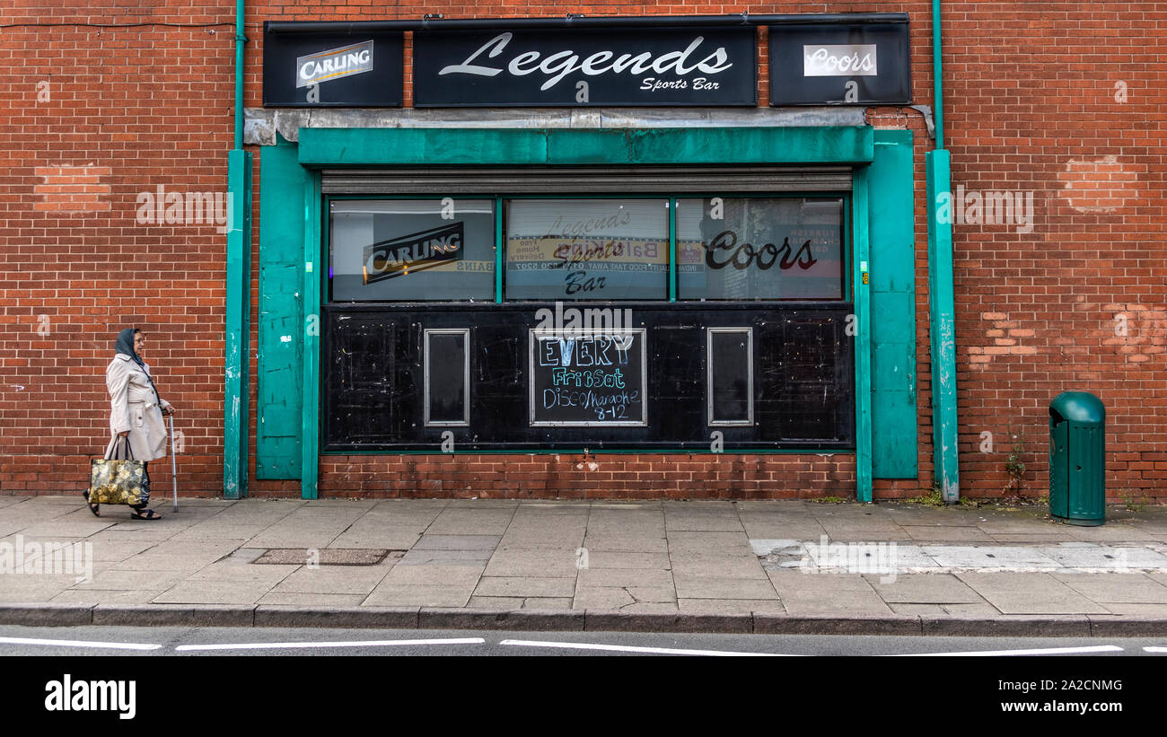 Elderly women walking past a sports bar in Tipton, northwest of Birmingham, West Midlands. It was once one of the most heavily industrialised towns in the Black Country, with thousands of people employed in the town's industries. Stock Photo