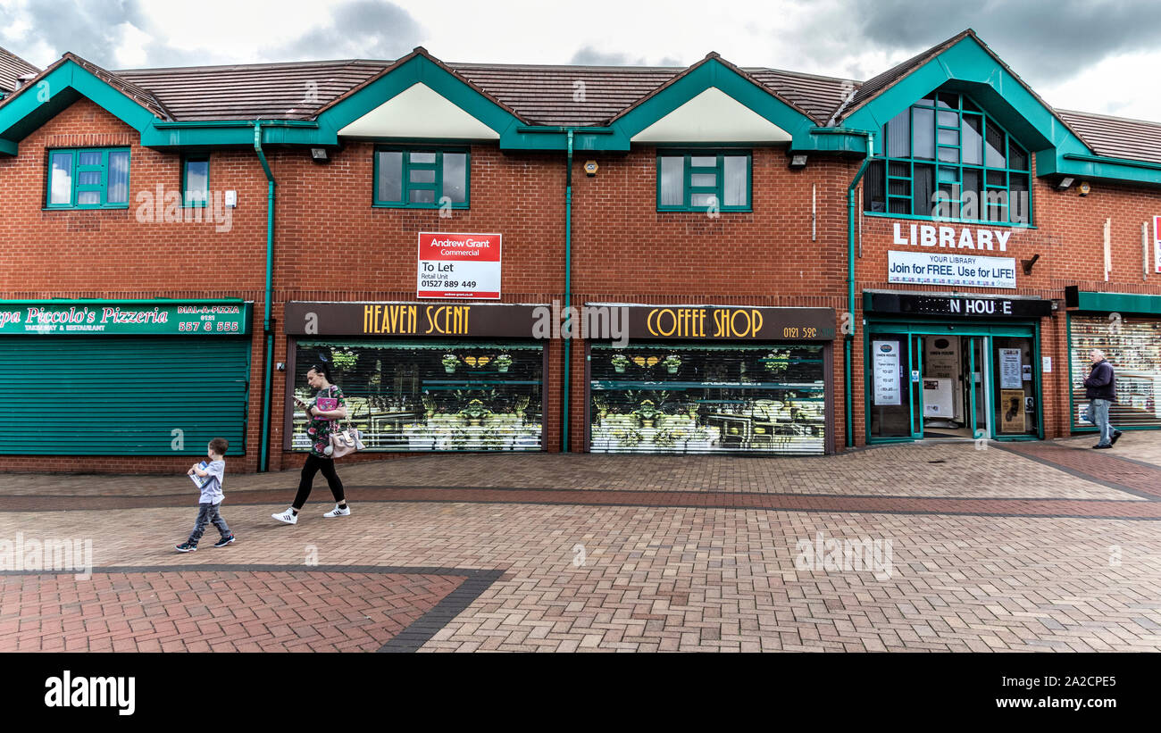 Elderly woman walking past closed down shops in the pedestrian precinct are of Tipton, northwest of Birmingham, West Midlands, UK  With a commercial property let sign in the background. Stock Photo