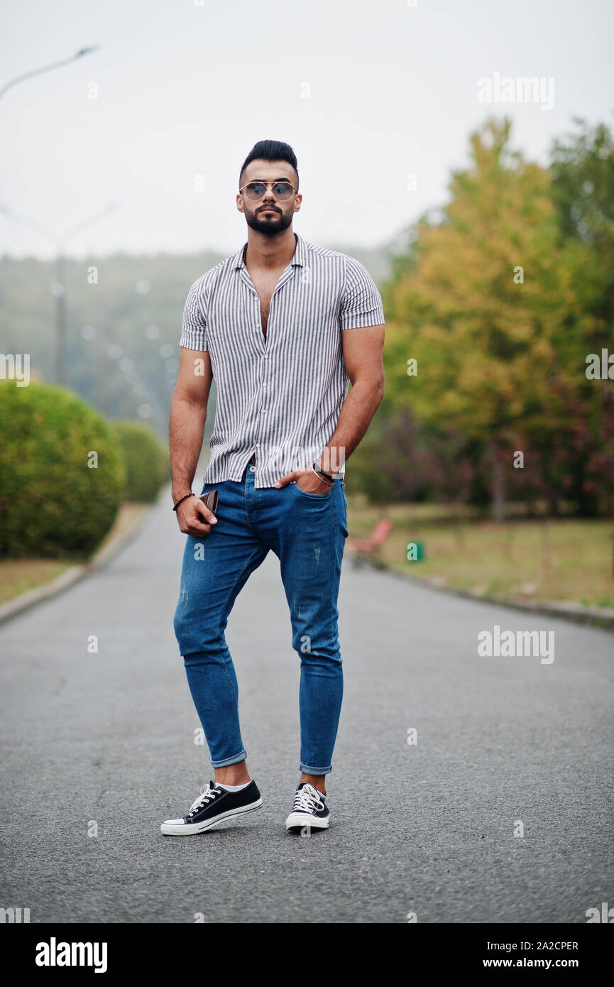 Fashionable tall arab beard man wear on shirt, jeans and sunglasses posed  on park and hold wallet at hand Stock Photo - Alamy