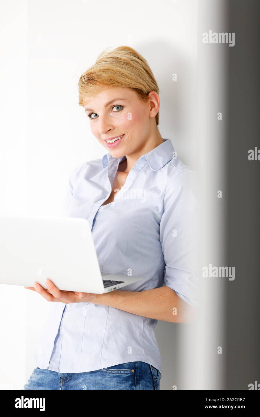 Attractive young woman using her laptop computer smiling Stock Photo