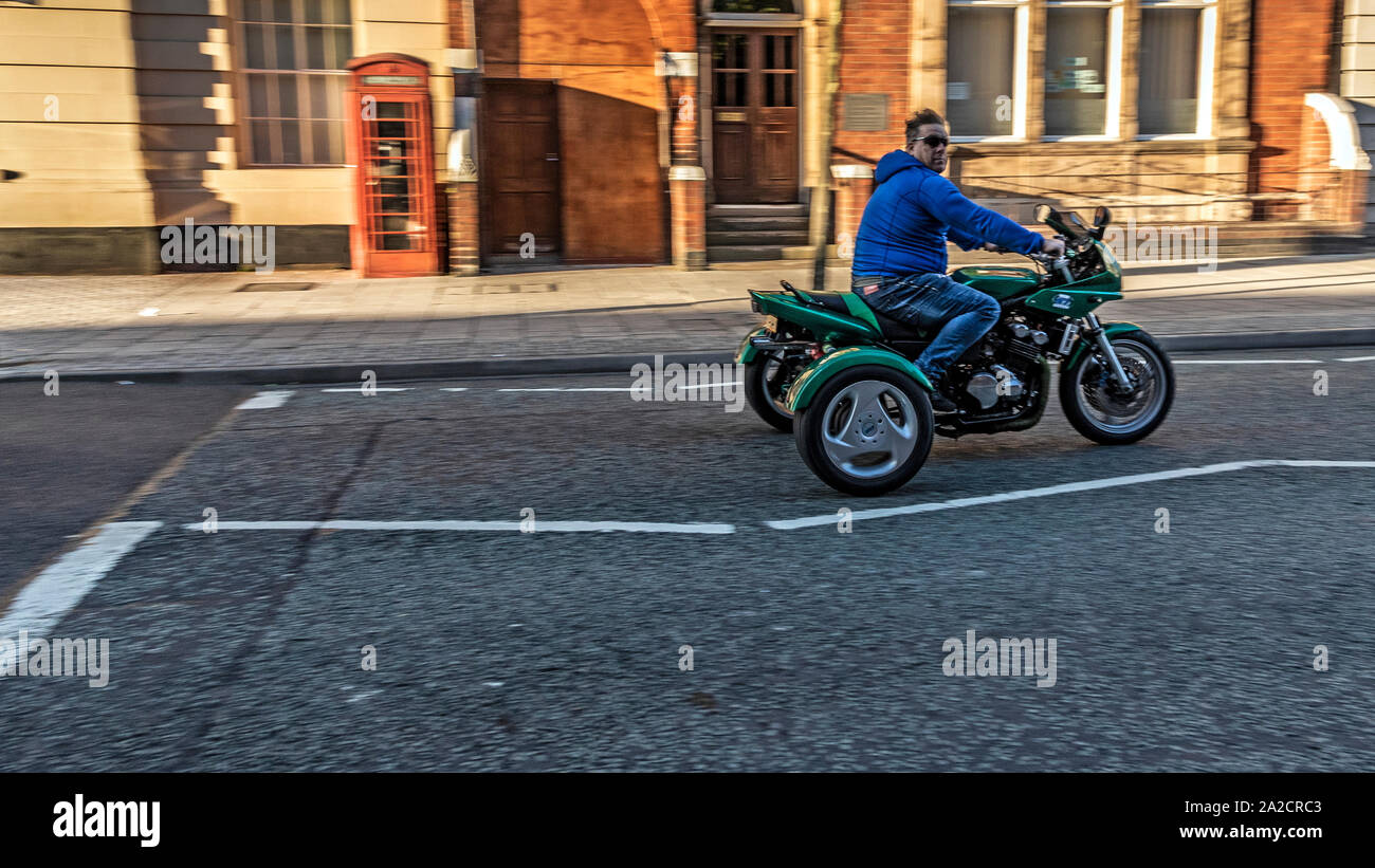 Young male riding quad bike down high street, West Bromwich, West Midlands, UK. Stock Photo