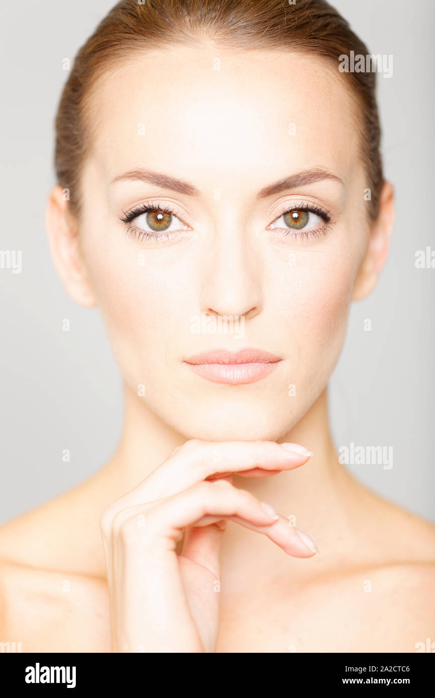 Beautiful young womans face with her hand resting on her chin in a