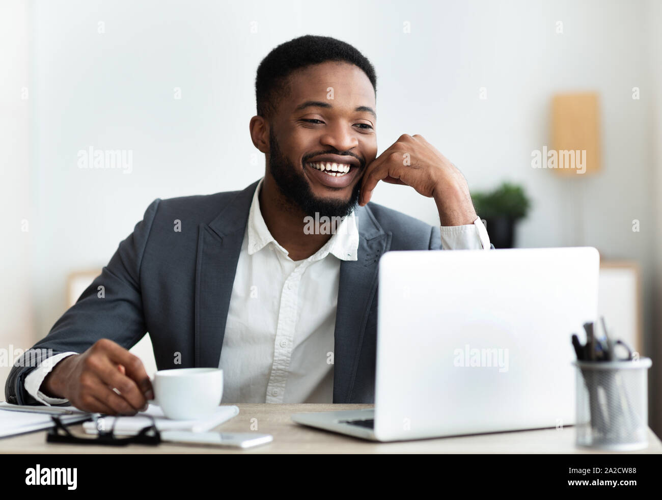 Cheerful african american employee sitting at workplace in modern office Stock Photo