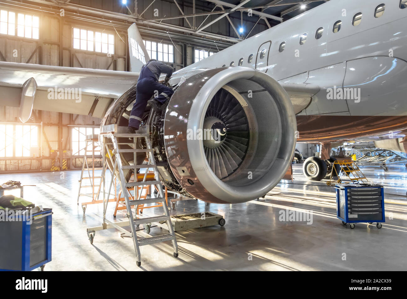 Mechanic specialist repairs the maintenance of engine of a passenger aircraft in a hangar. Stock Photo