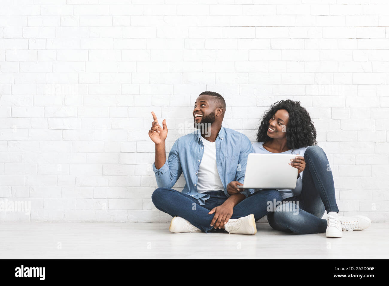 Young couple with laptop pointing at empty space Stock Photo