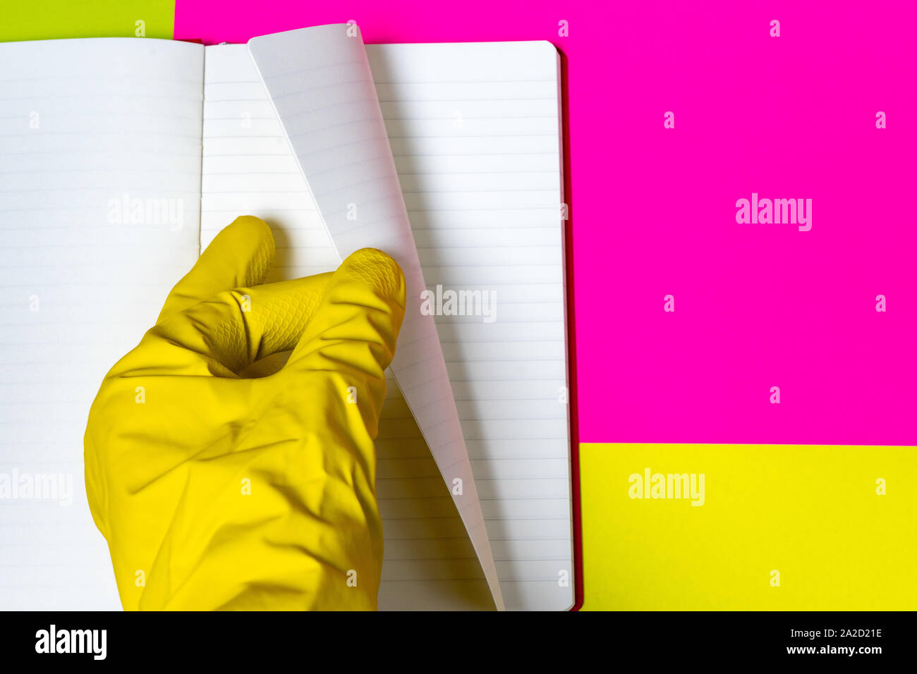 Hands in rubber gloves carefully turn the page of an empty magazine. Bright background of pink and yellow. Stock Photo